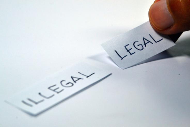 Zwei Papierschnipsel mit der Aufschrift "Illegal" und "Legal".